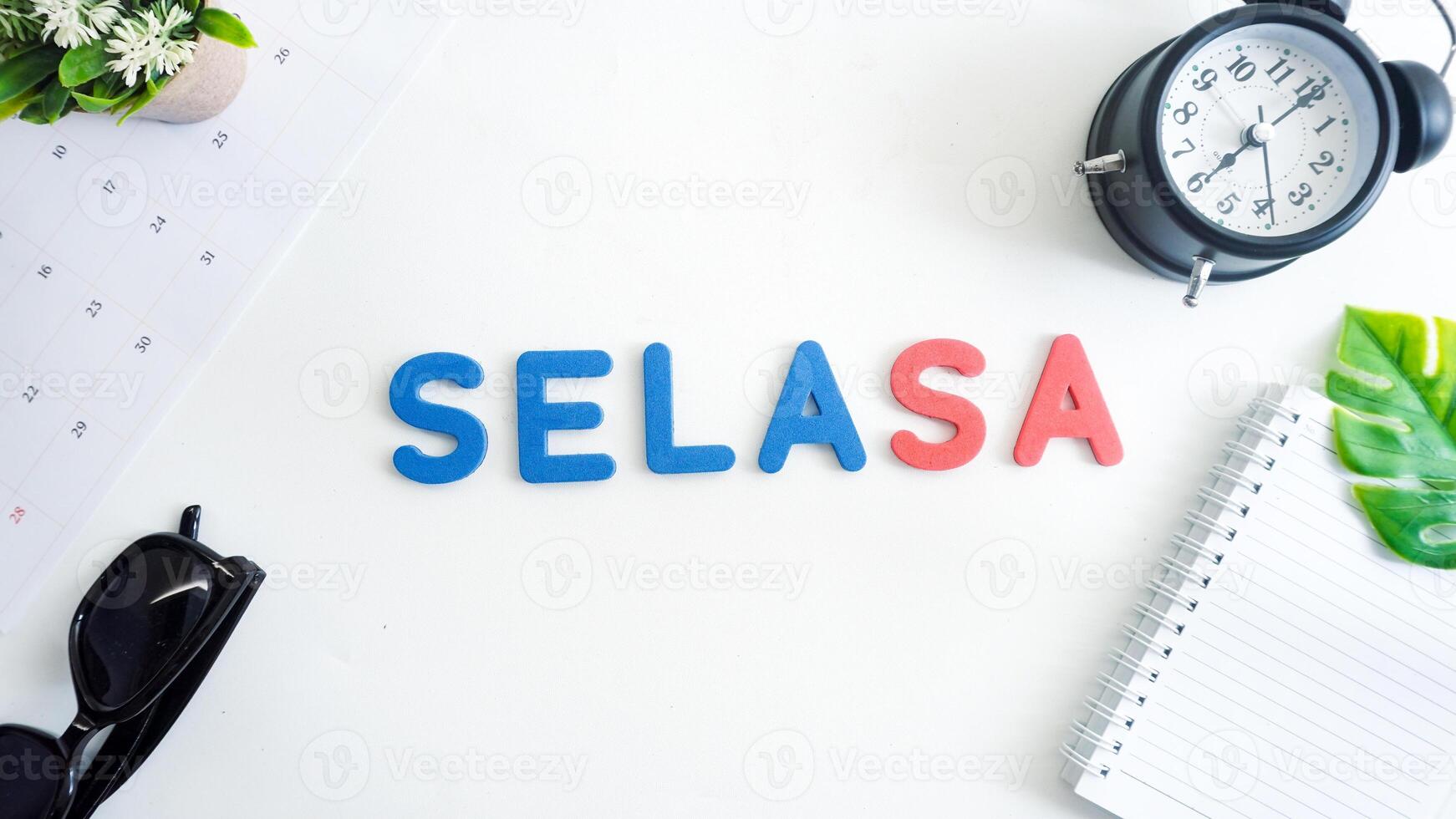 Flat lay composition with red and blue color foam letters spelling word tuesday in Indonesian, SELASA isolated on white background photo