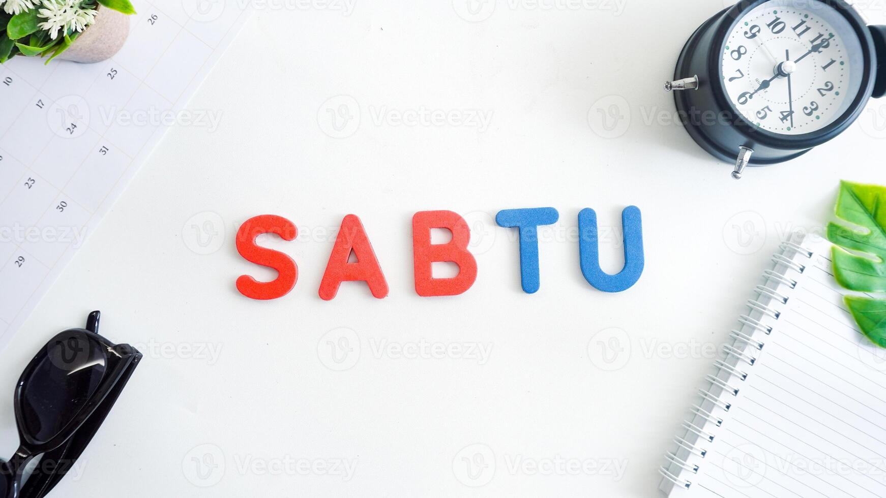 Flat lay composition with blue and red color foam letters spelling word saturday in Indonesian, SABTU isolated on white background photo
