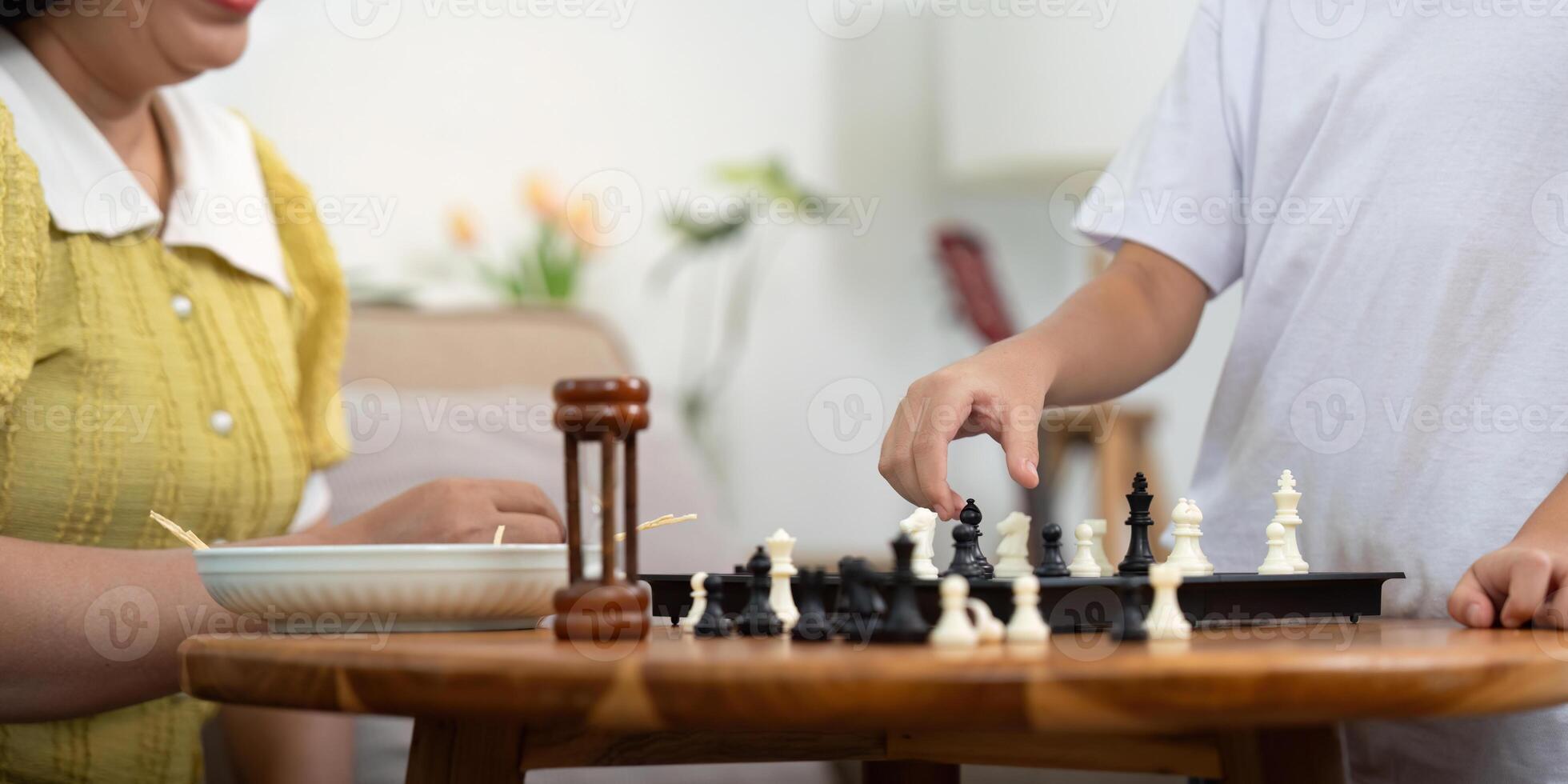 Child Strategizing Chess Move While Mother Observes photo