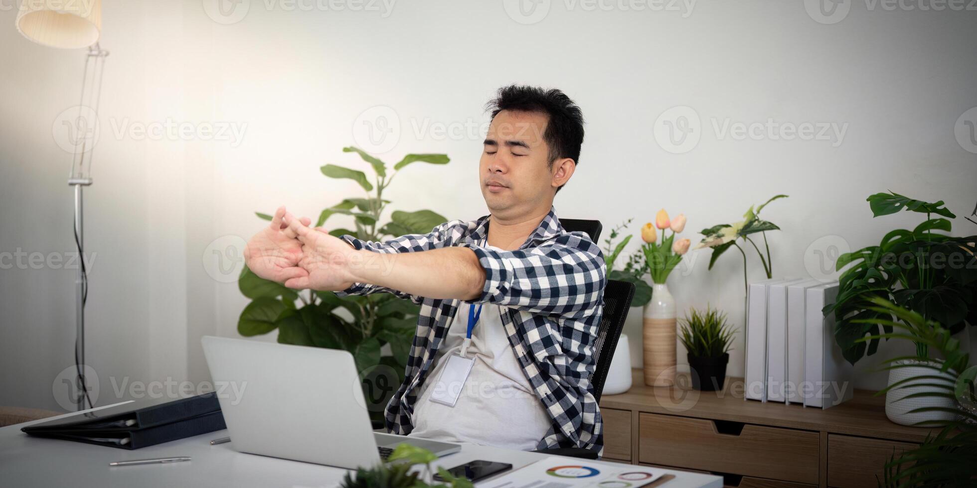 Wellness. Young man stretching at his desk for better health and productivity. photo