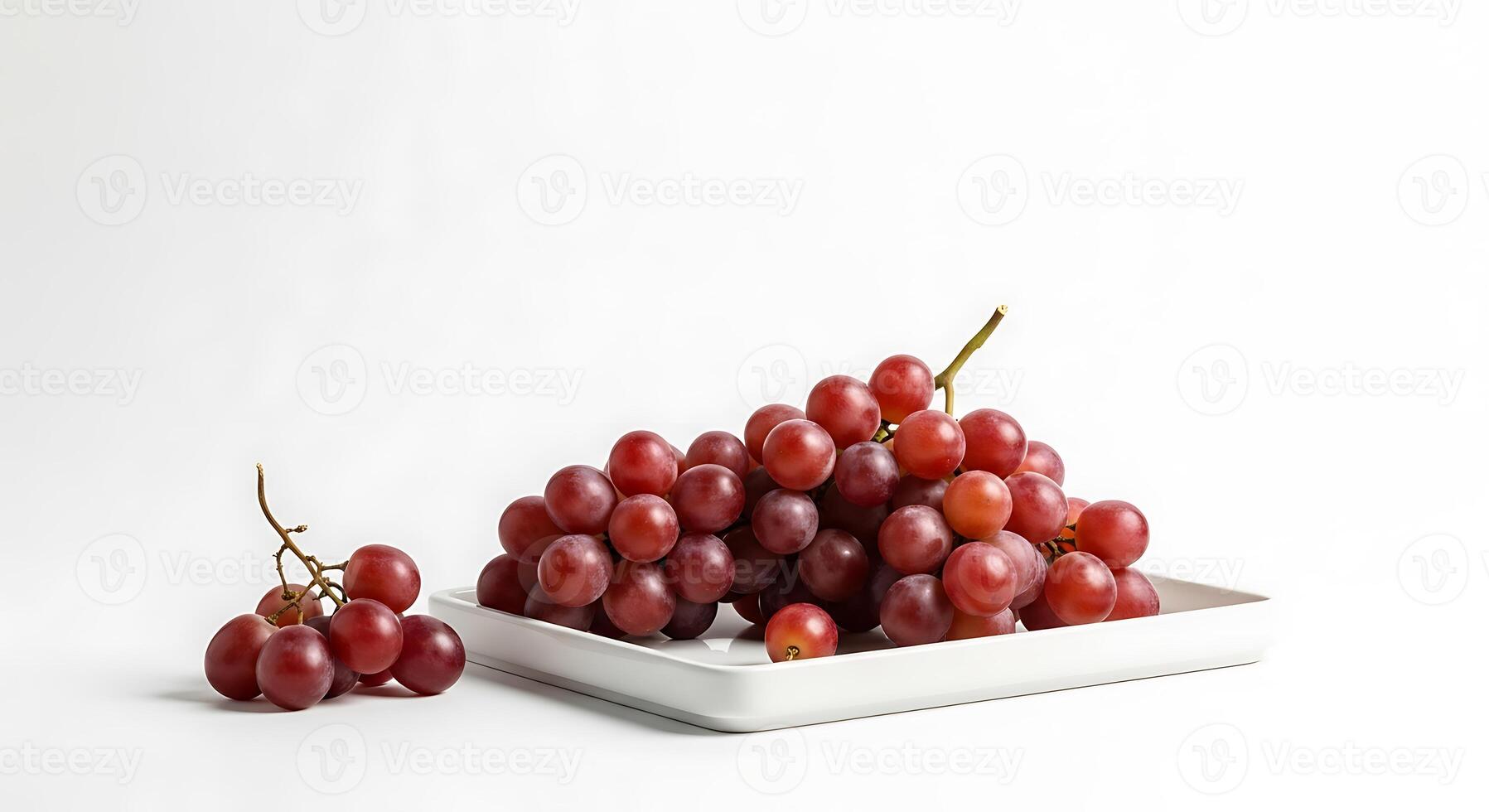 Fresh red grapes on a white plate with a small bunch on the side photo