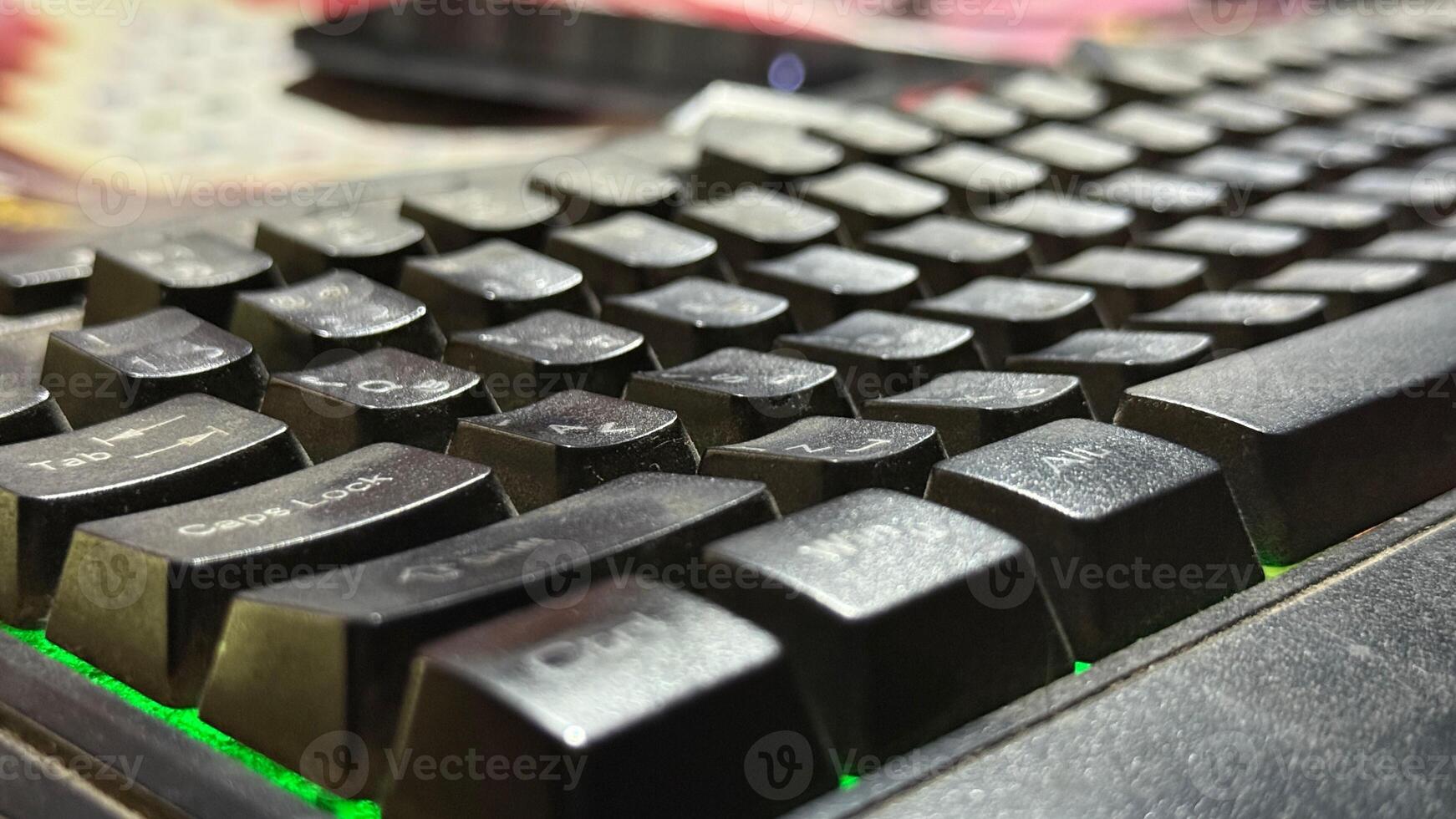 Close view shows a black dusty keyboard with green led lighting effect on display photo