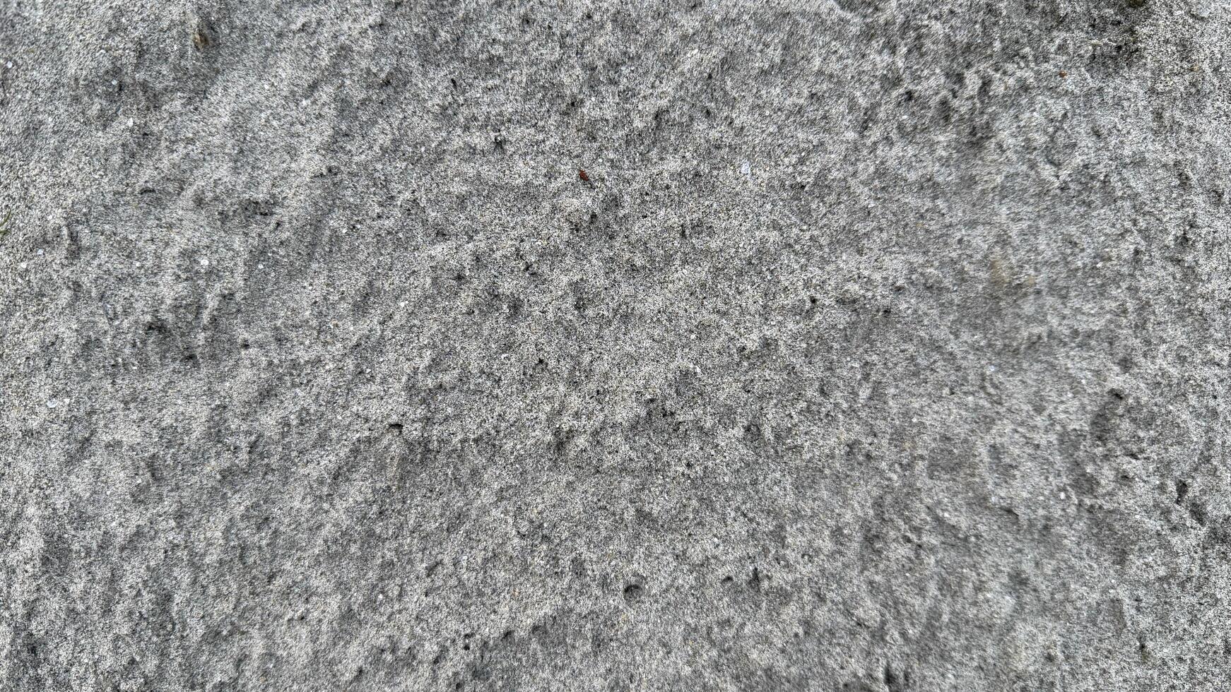 A rough stone and concrete wall texture with a gray grunge pattern provides a dirty, old backdrop surface photo
