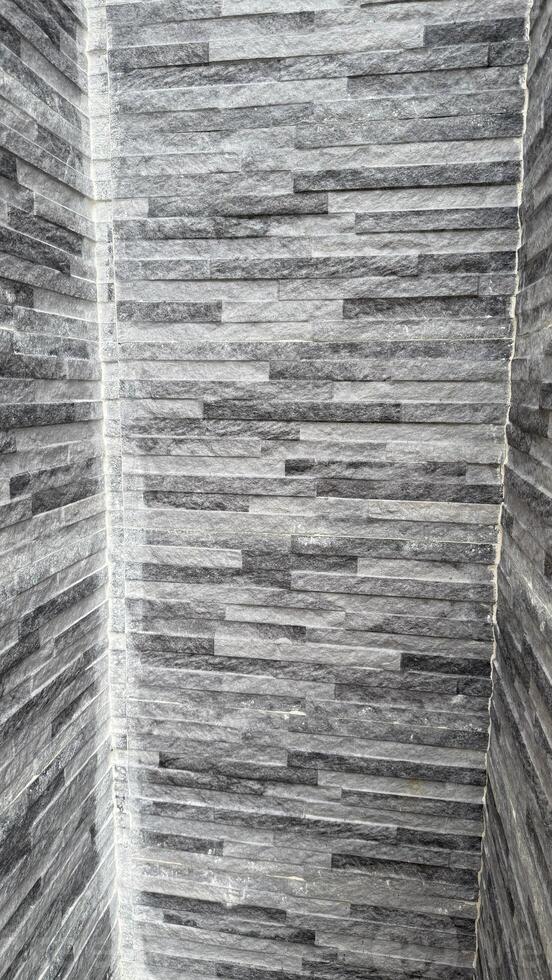 Interior corner showcases a gray textured stone wall with horizontal brickwork creating a modern aesthetic photo
