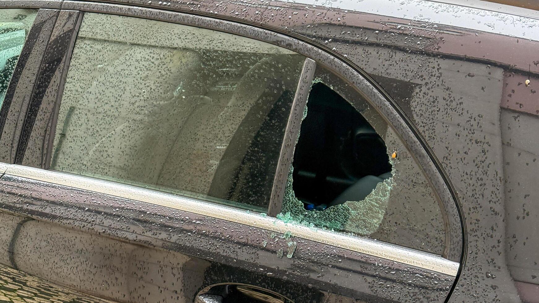 Shattered car window glistens in twilight drizzle, urban silence, echo of mischief, Mischief Night or Solitary Reflection Day photo