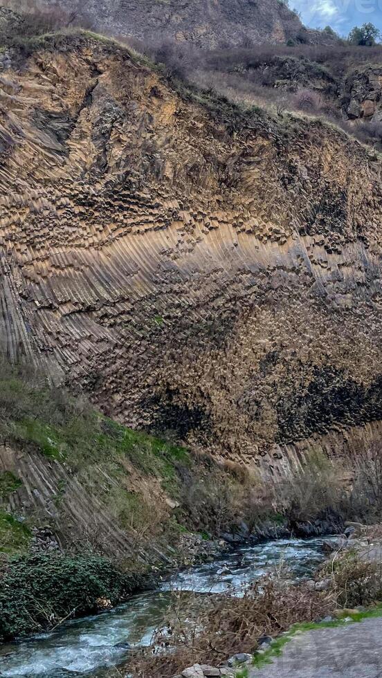 Rugged basalt cliff whispering ancient secrets above a murmuring brook, perfect for Earth Day or Geologists Day explorations photo