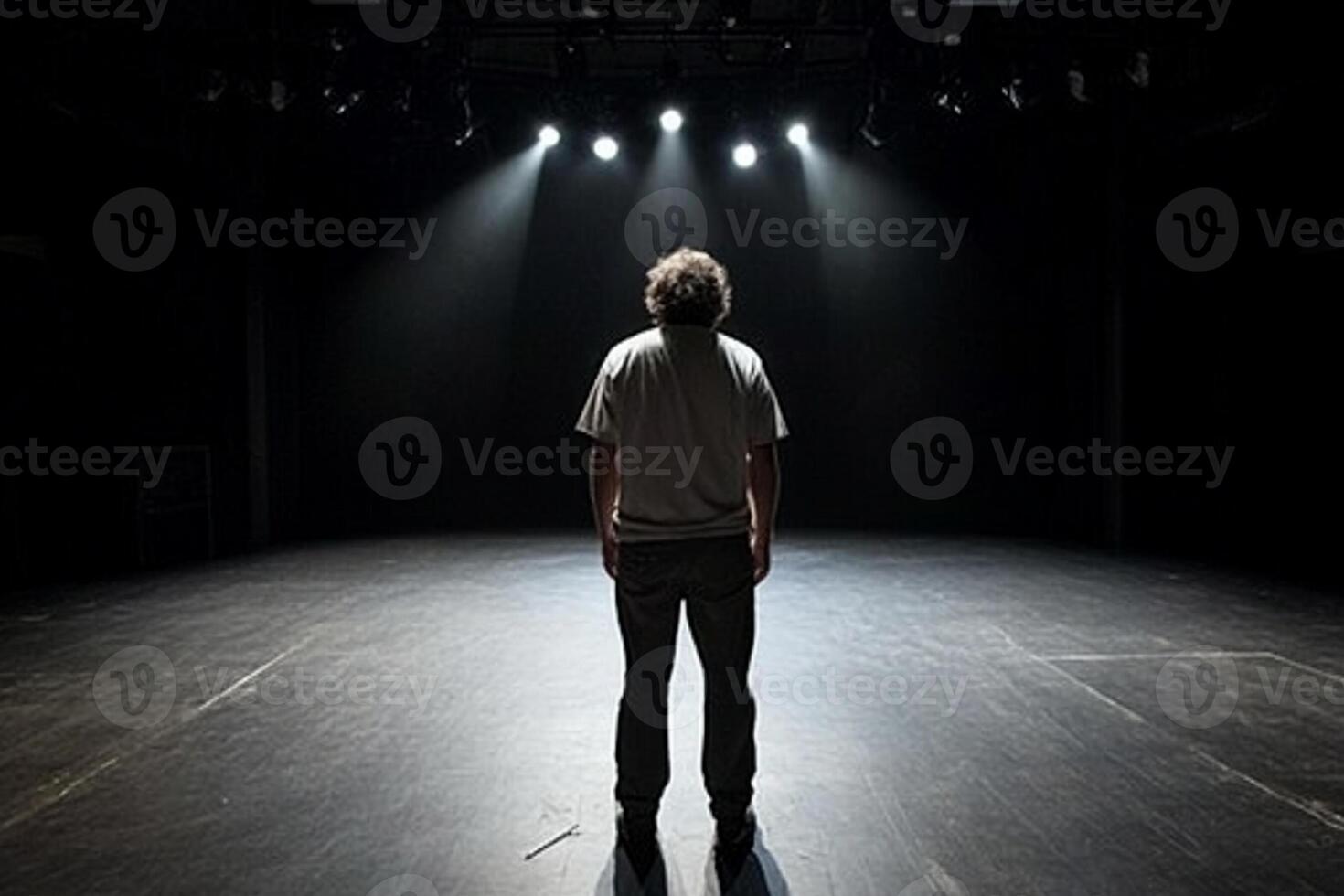 A man standing in the middle of a dark stage photo