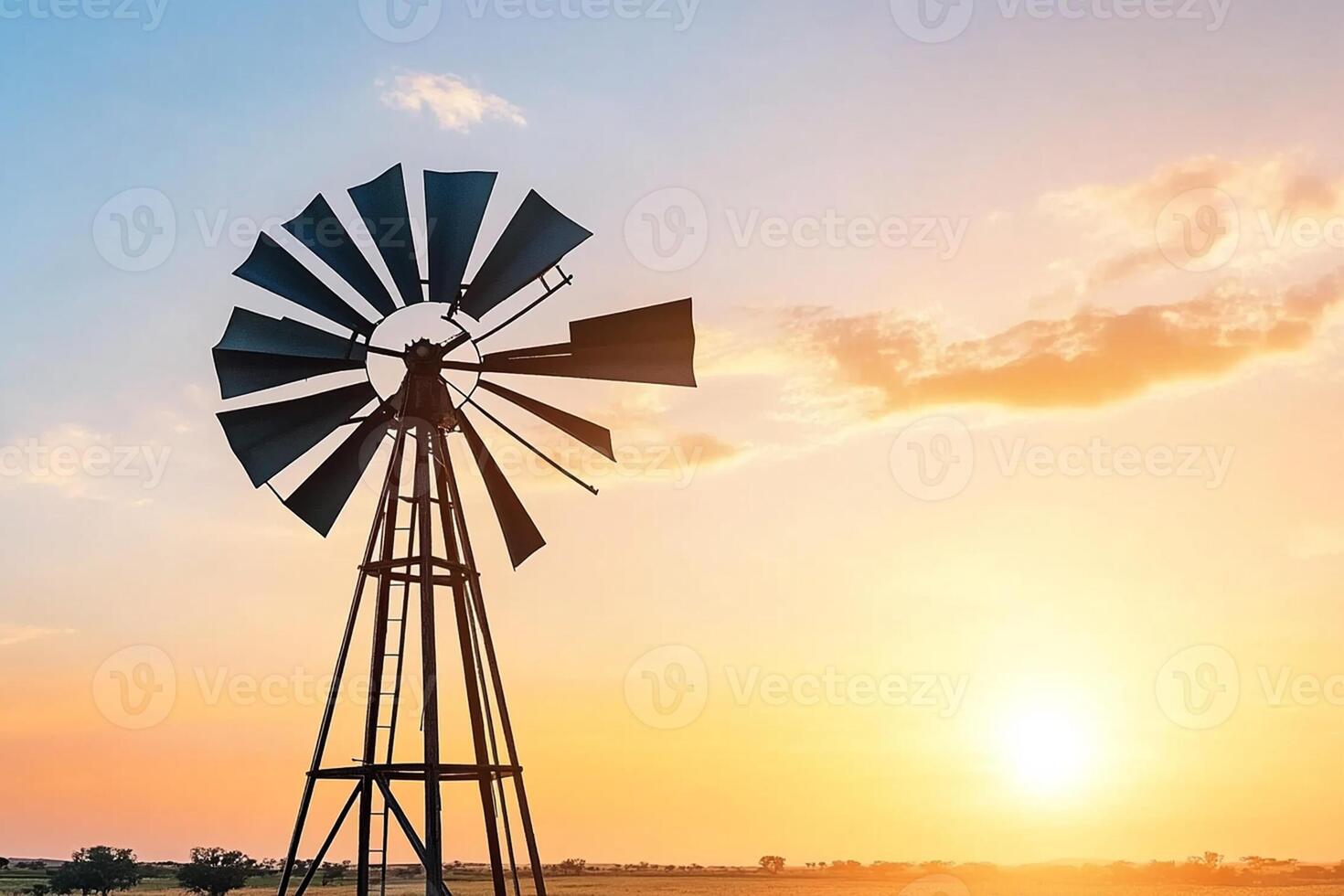 A windmill is silhouetted against a sunset sky photo