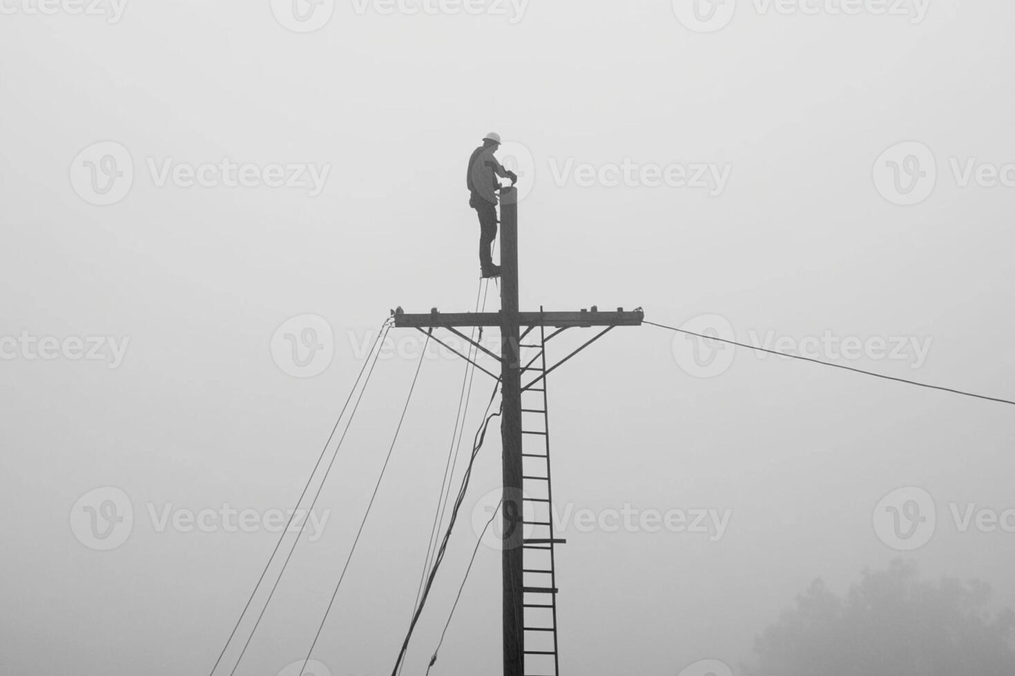 A man standing on top of a power pole in the fog photo