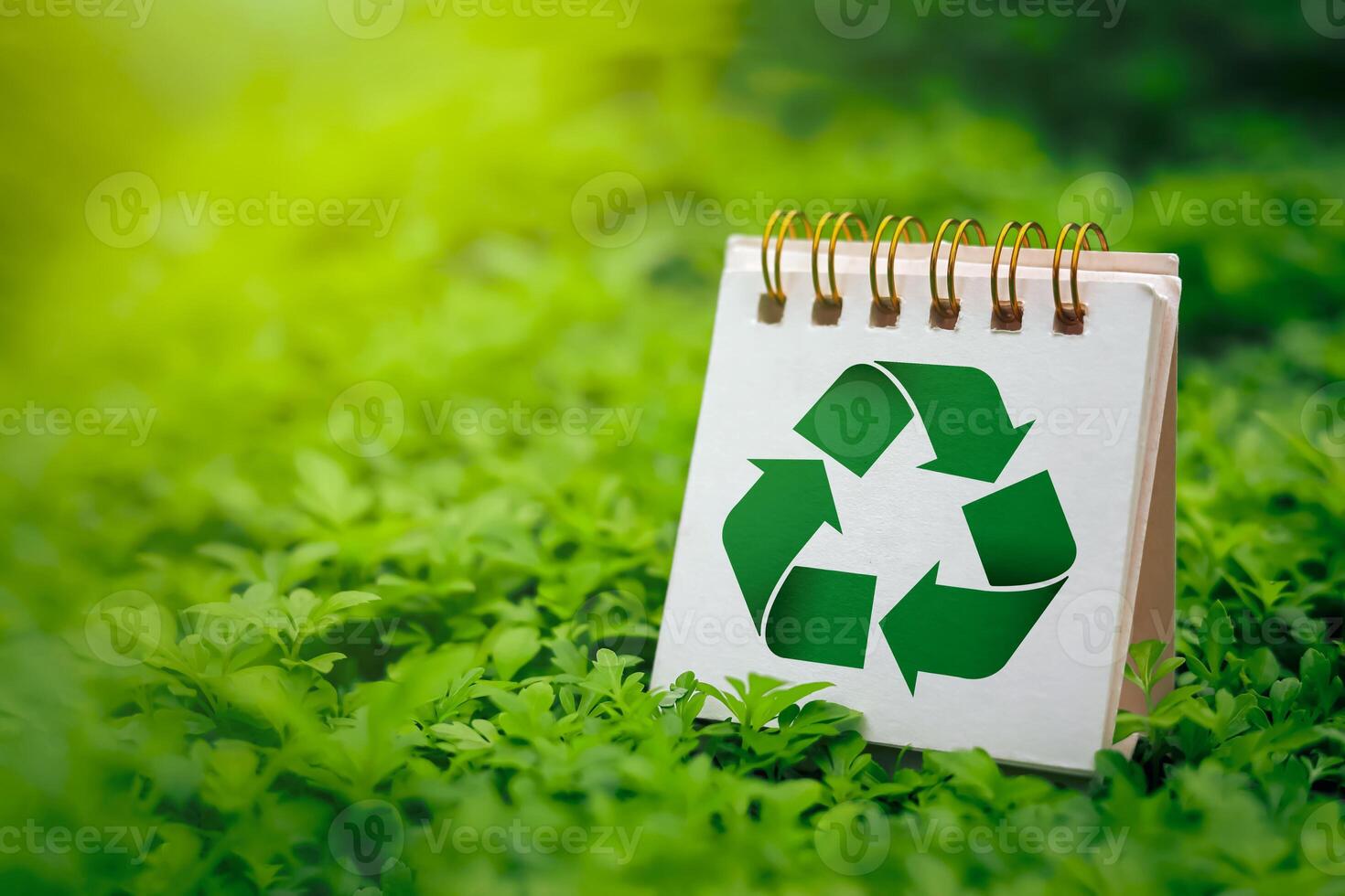 Green recycling symbol on small calendar with fresh green grass background. Concepts of reducing and reusing, environmentally friendly products, CSR, zero waste. with copy space photo