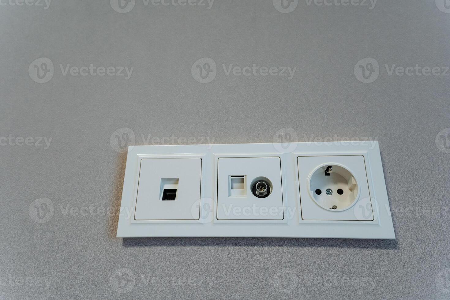 This image features a detailed close up view of a white electrical outlet that is mounted on a surface of a wall, providing access to AC power and electricity in the room photo