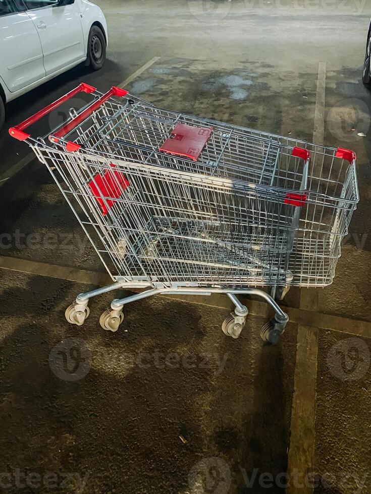 In a busy parking lot, there is a shopping cart that has been parked adjacent to a pristine white car, creating a scene that many shoppers might come across during their errands photo