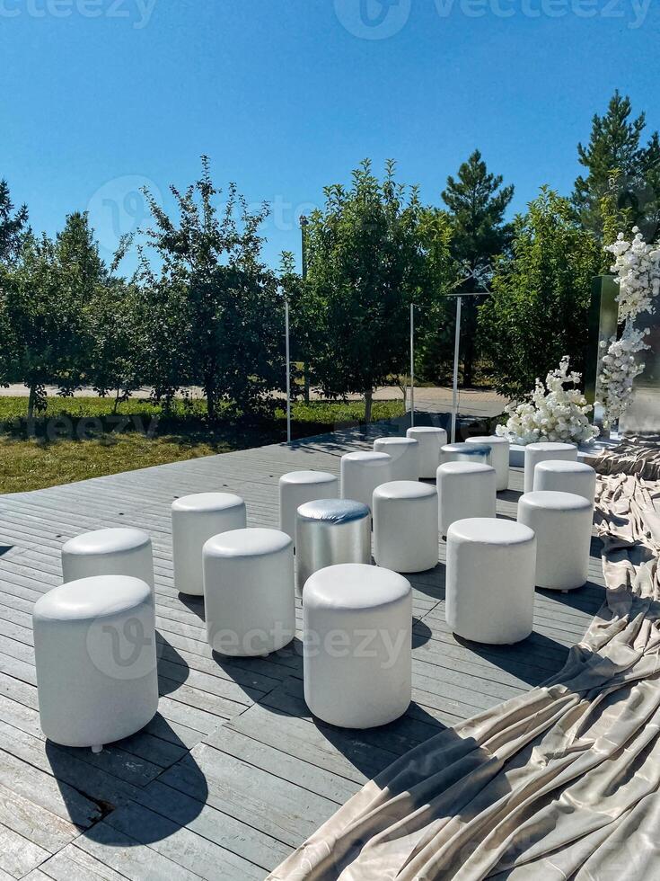 A neat and stylish row of white ottomans is positioned on a wellmaintained wooden deck, adding comfort and elegance to the outdoor living space in a visually appealing manner photo