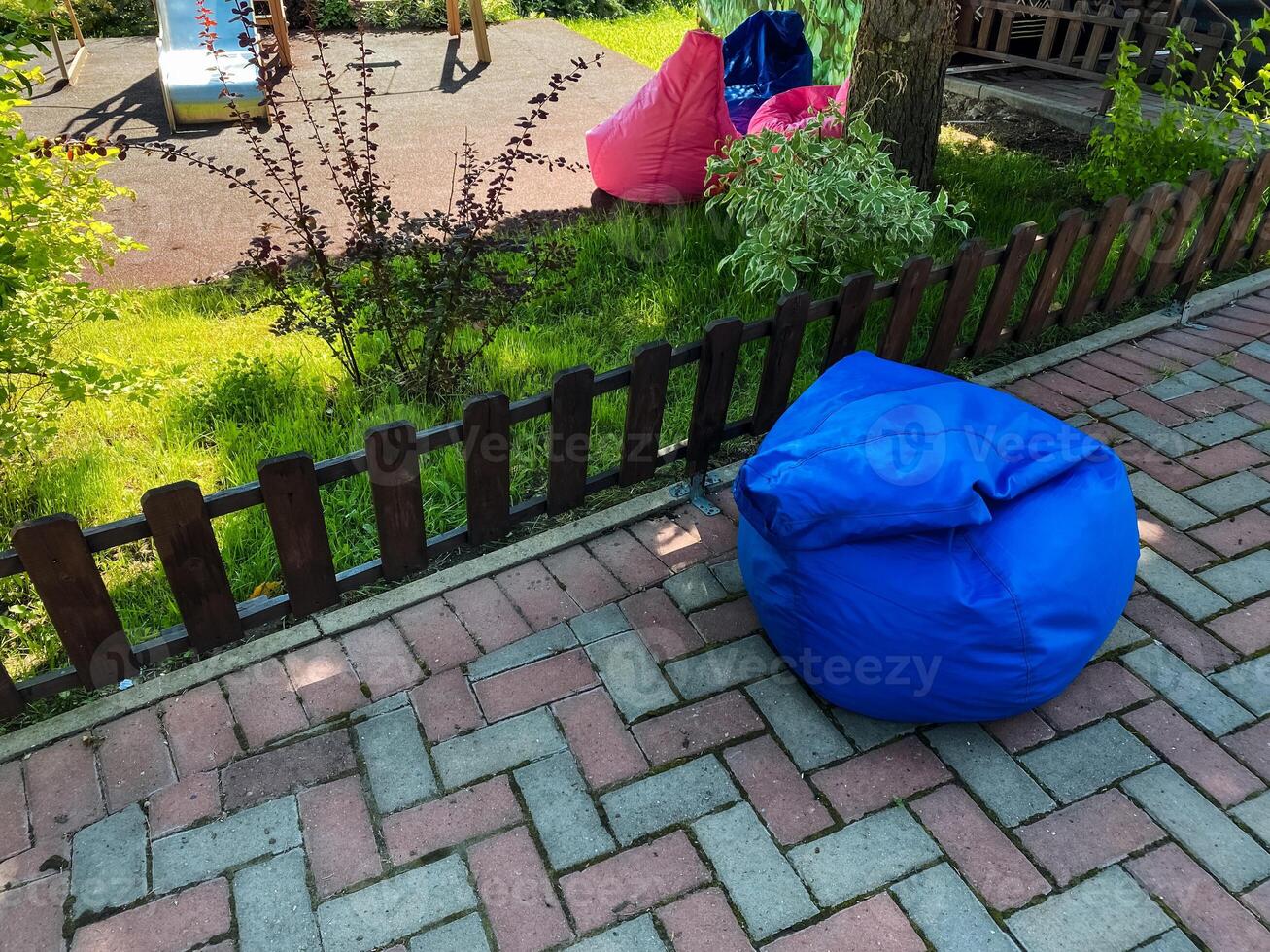 A vibrant blue bean bag chair, with its plush fabric, sits on a charming brick sidewalk, creating a cozy and inviting atmosphere for relaxation in a serene outdoor setting photo