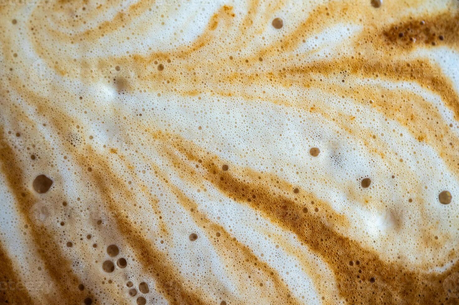 Full frame shot of the surface of hot latte coffee. A latte is a coffee drink made with espresso and steamed milk. photo