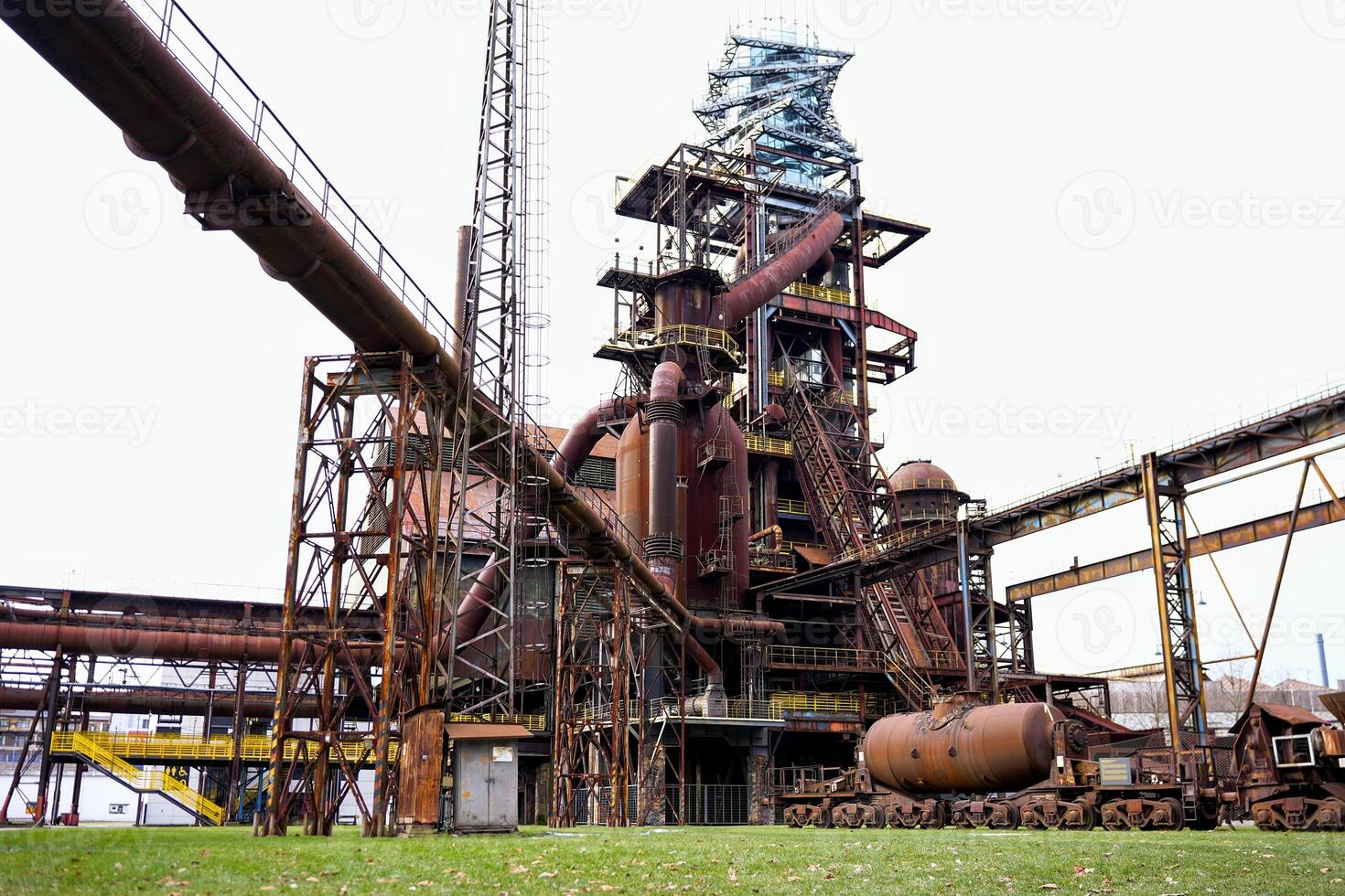 Industrial blast furnace and rusted railway tank at abandoned steelworks photo