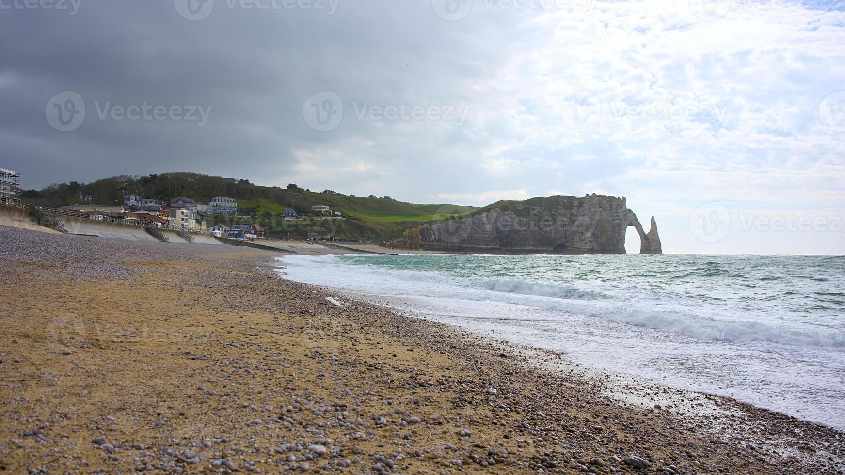 Etretat seashore with sea arch and village in cloudy light photo