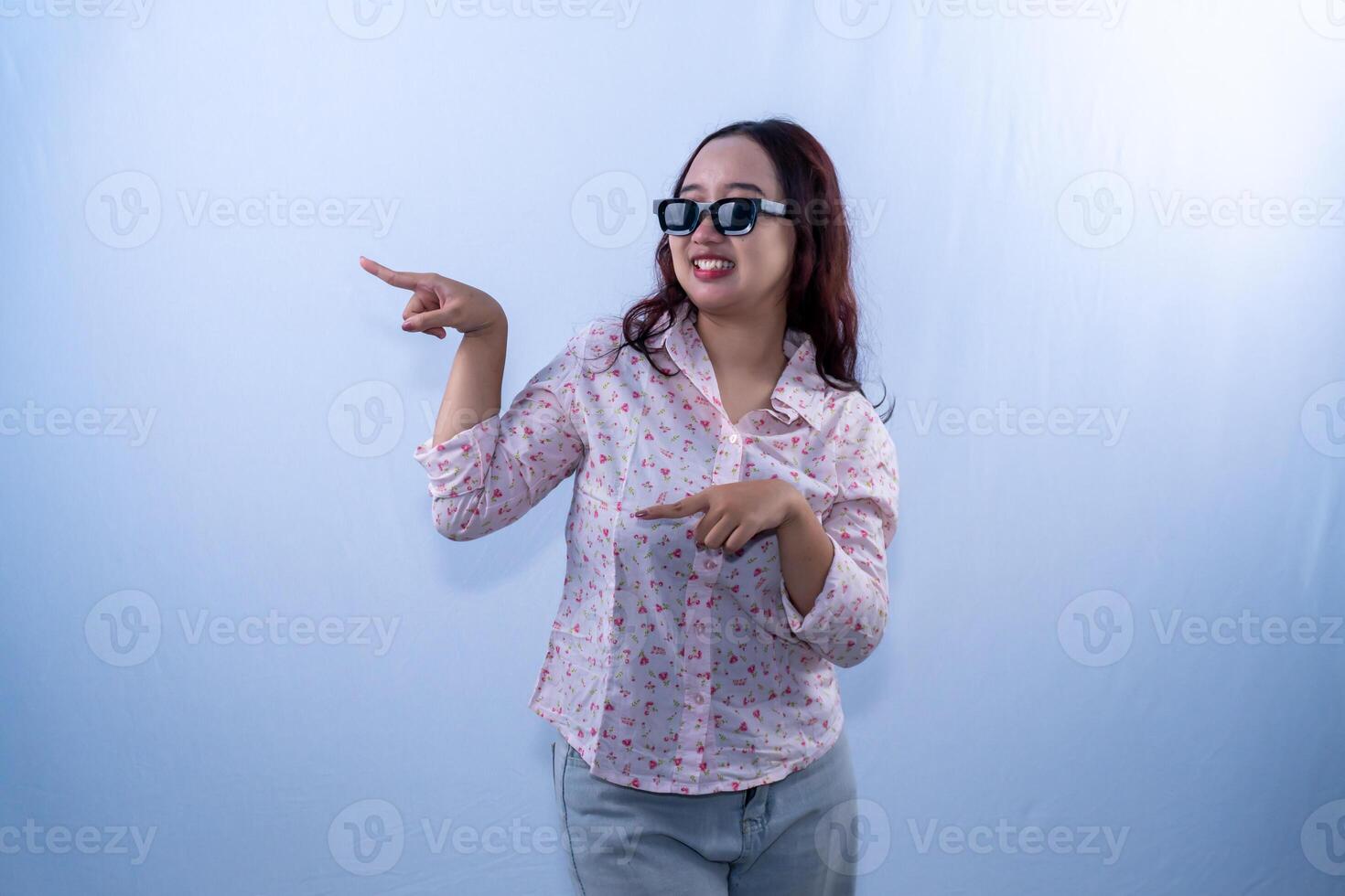Asian Indonesian woman wearing white floral patterned dress wearing glasses pointing to the side photo