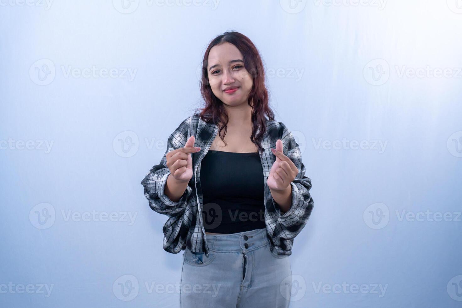Indonesian Asian woman wearing a checkered shirt smiling and giving a love sign with her fingers photo
