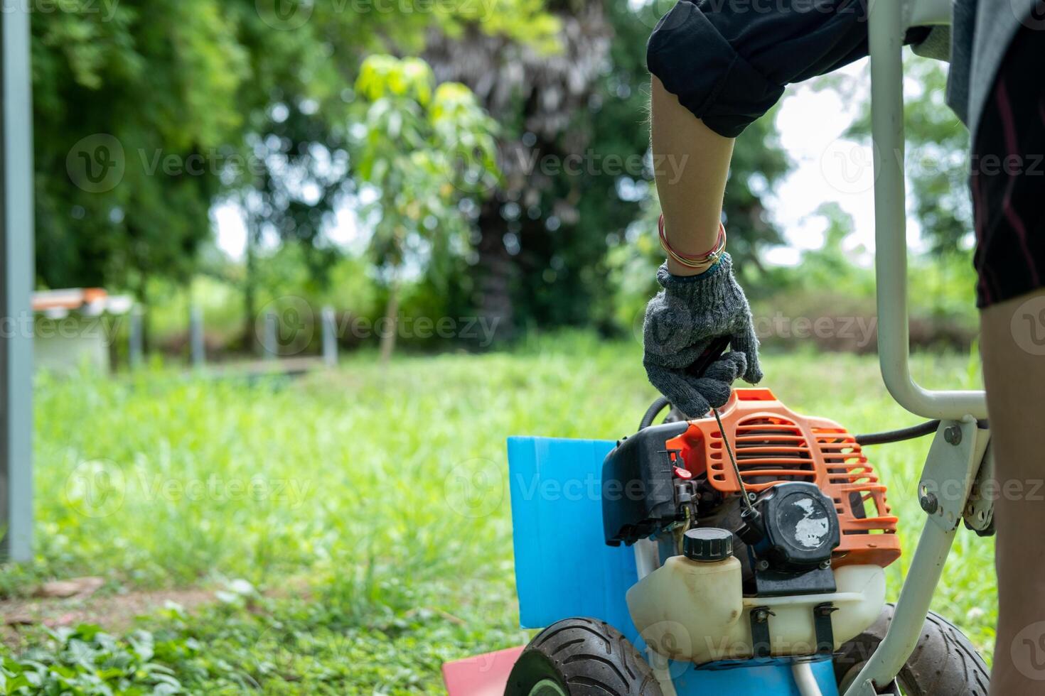 Man pulling lawnmower starter cord, beginning the task of trimming a tidy green lawn. photo