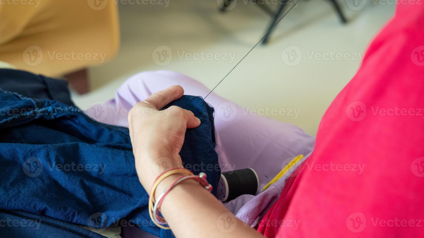 Close up of a mother hands sewing trouser legs, showing family care through homemade mending. photo