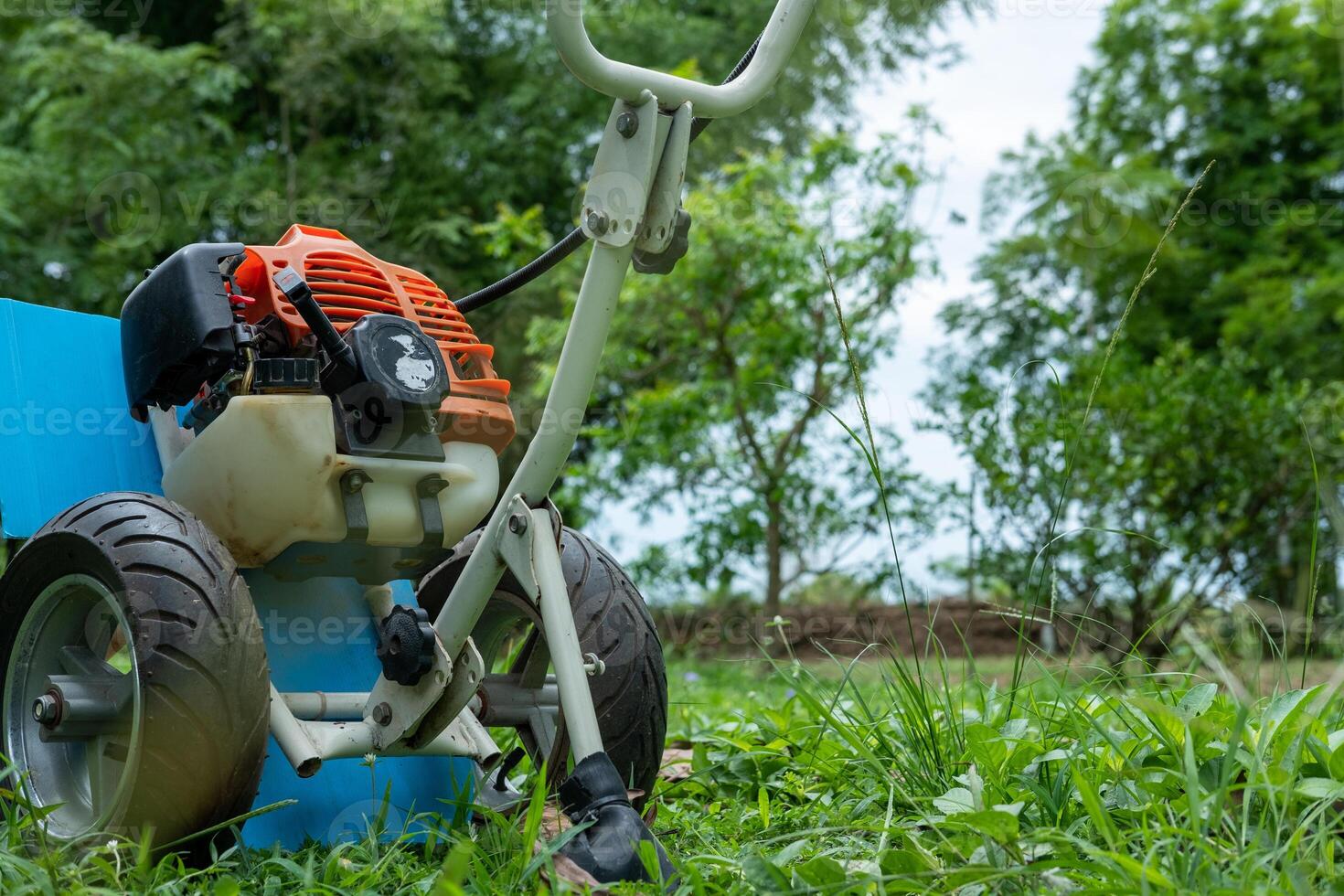 Lawn mower parked on green grass, ready for mowing the lawn and garden maintenance work. photo