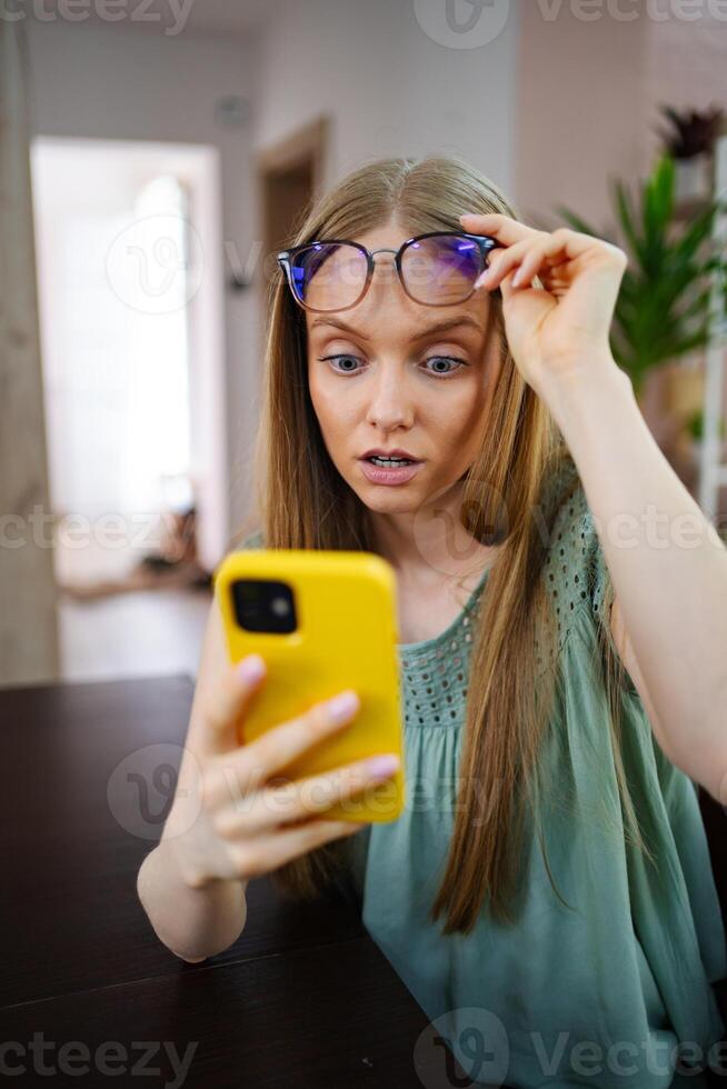 Surprised girl discovers unexpected news while using her smartphone photo