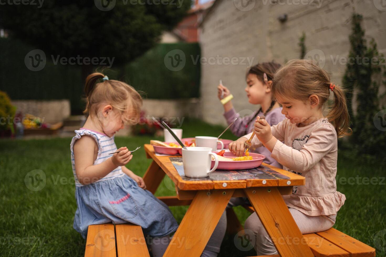 Children enjoy a joyful meal together in a vibrant garden setting photo