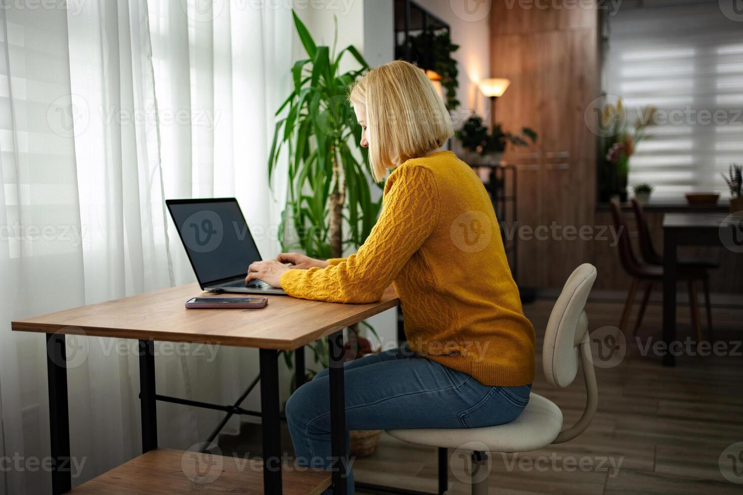 Focused individual engaged in productive work at a stylish home office space during the afternoon photo