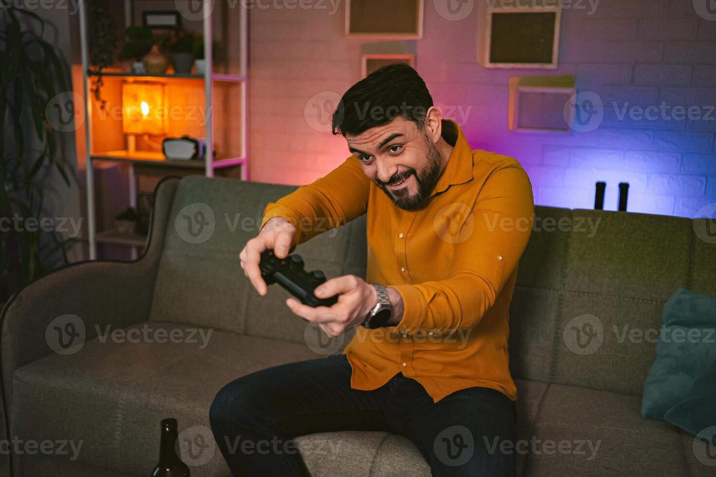 Excitement fills the room as a man immerses himself in an intense game session during a cozy evening at home photo