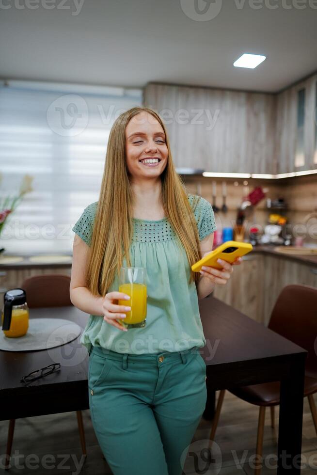 Happy woman enjoying a refreshing drink in a cozy kitchen photo