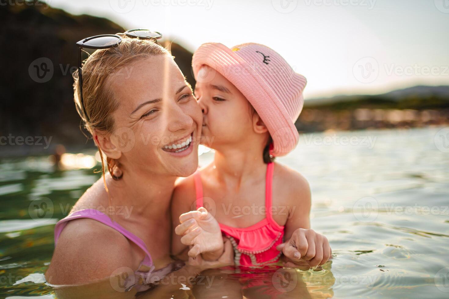 Joyful moments between mother and daughter at the beach during sunset photo