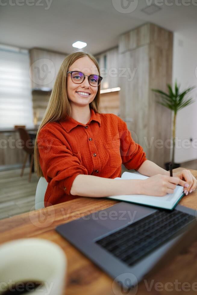 Focused young woman jotting down ideas in a cozy workspace photo