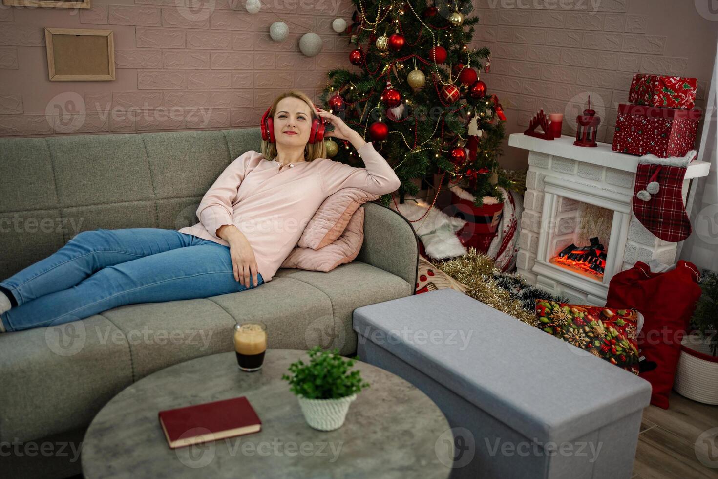 Relaxing by the fireplace, a woman enjoys a cozy moment in a festive living room decorated for the holidays photo
