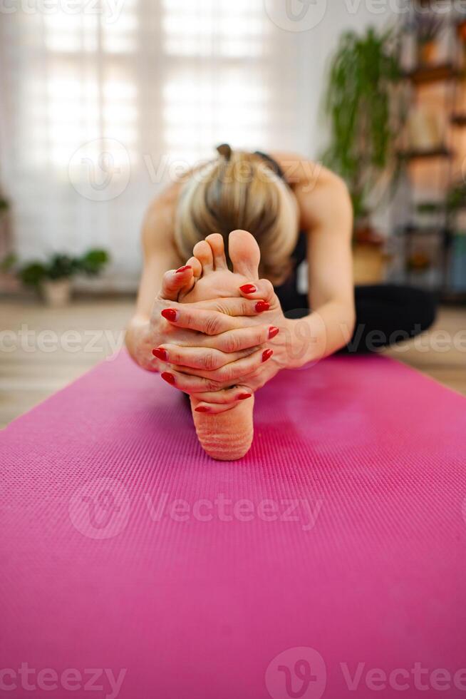 A person practices yoga, reaching for their toes in a sunlit space photo