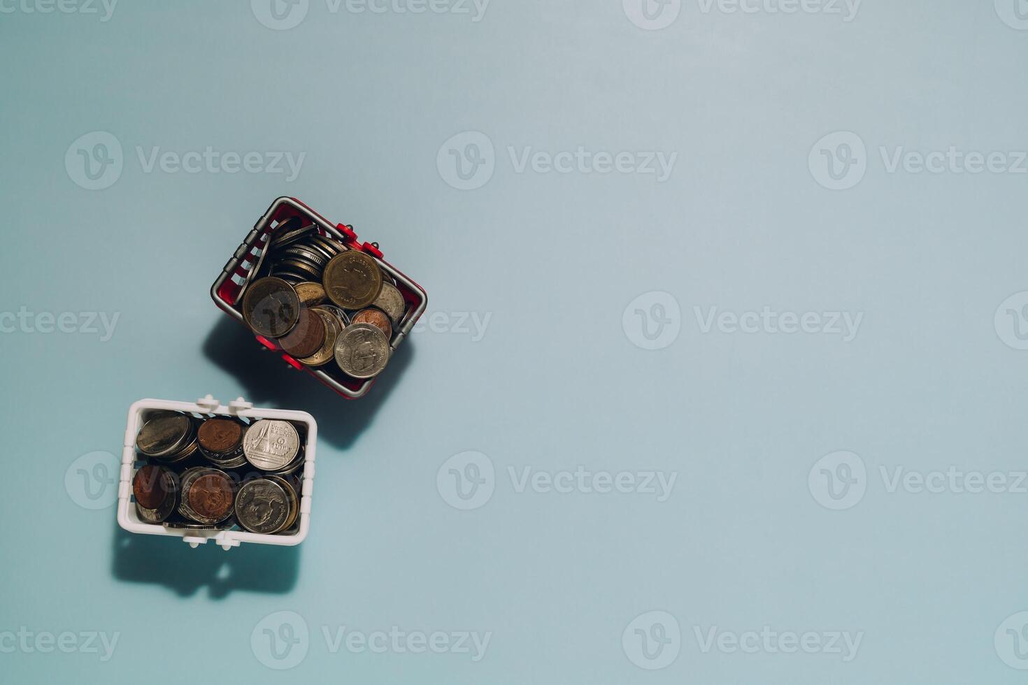 Two Mini Shopping Baskets Full of Coins on Blue photo
