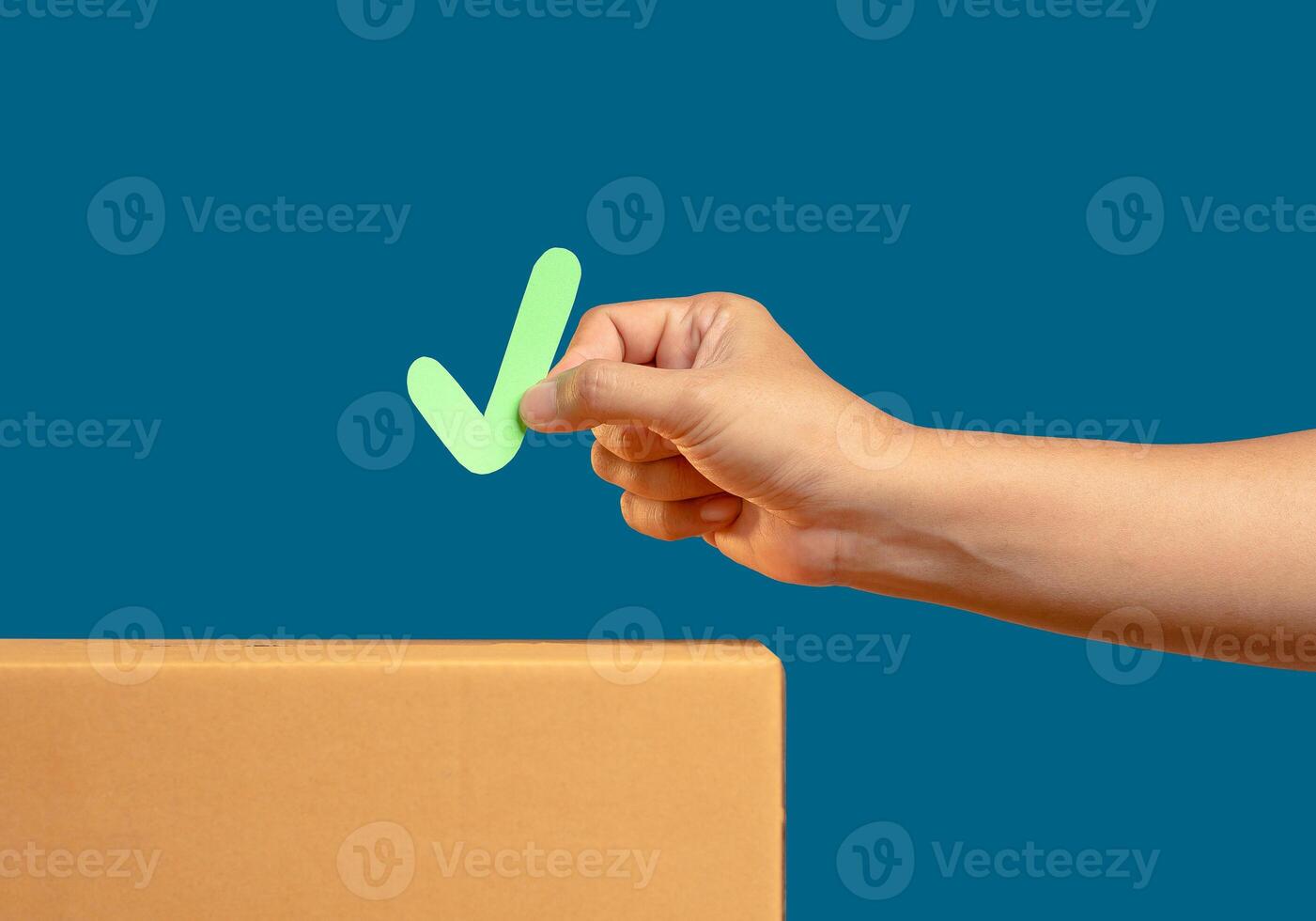 Hand holding a green check mark symbol hovers above a voting box against a blue background at an election site photo