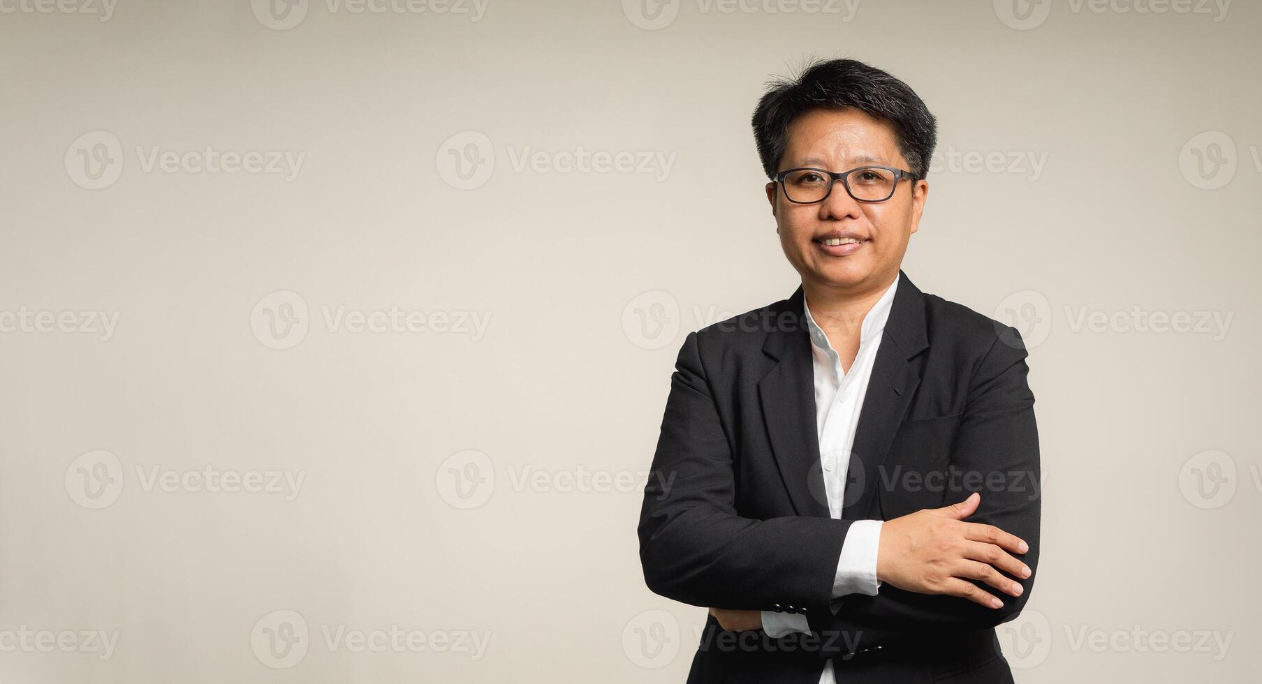 Portrait of a businesswoman with short black hair with a smile while standing with arms crossed on a gray background photo