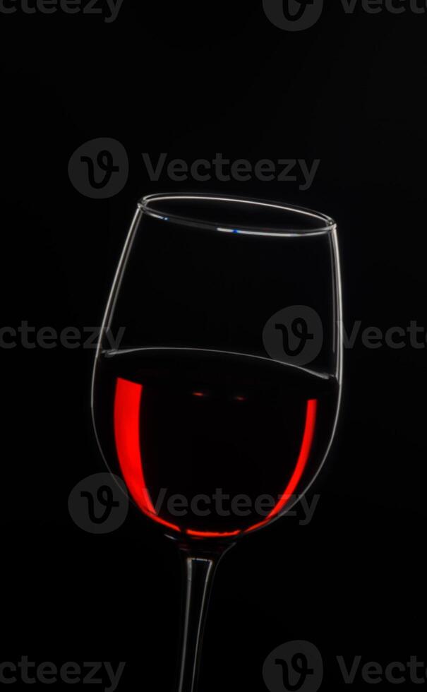 Elegant glass filled with rich red wine captured against a dark background photo