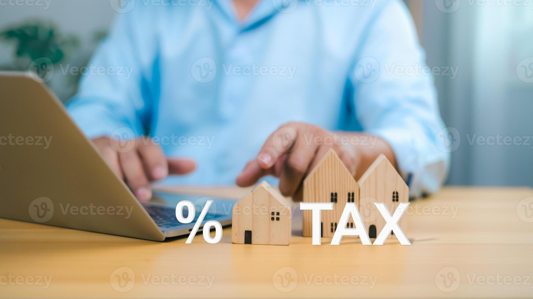 Tax property planning with a businessman using a laptop and wooden house models to represent real estate investment and financial calculation. photo