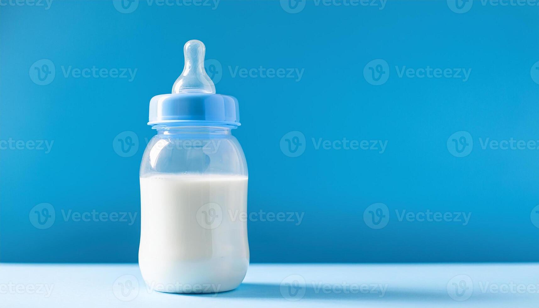 Plastic baby milk bottle on blue backdrop. Feeding time. photo