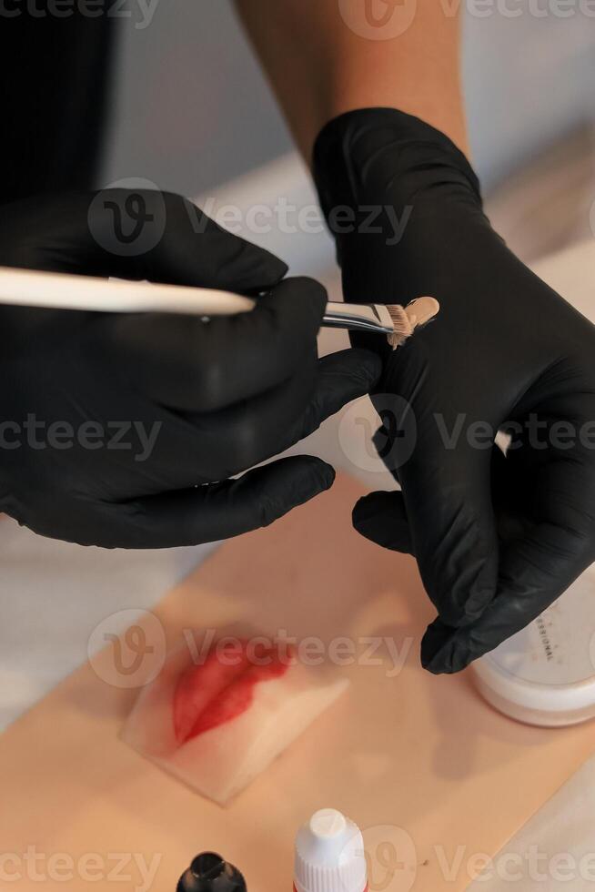 Makeup artist doing permanent makeup on silicone lips photo
