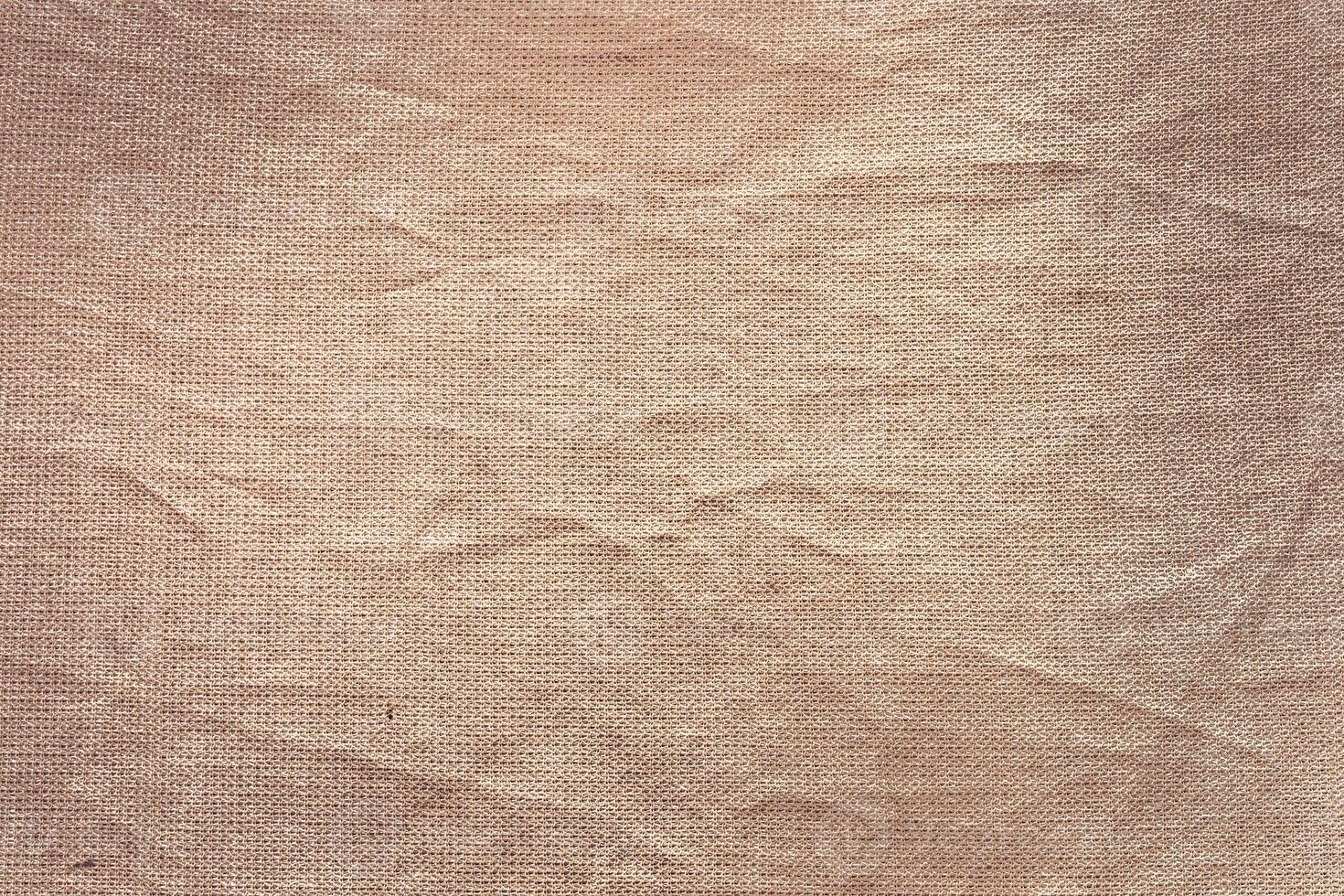 A close-up view of textured fabric with a soft, beige color. The surface shows subtle wrinkles and a natural, organic appearance. photo