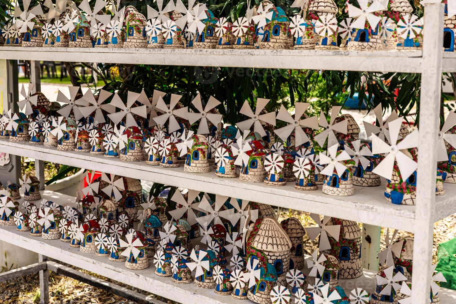 Colorful handmade windmills displayed on wooden shelves. The windmills feature intricate designs and vibrant colors, showcasing traditional craftsmanship. photo
