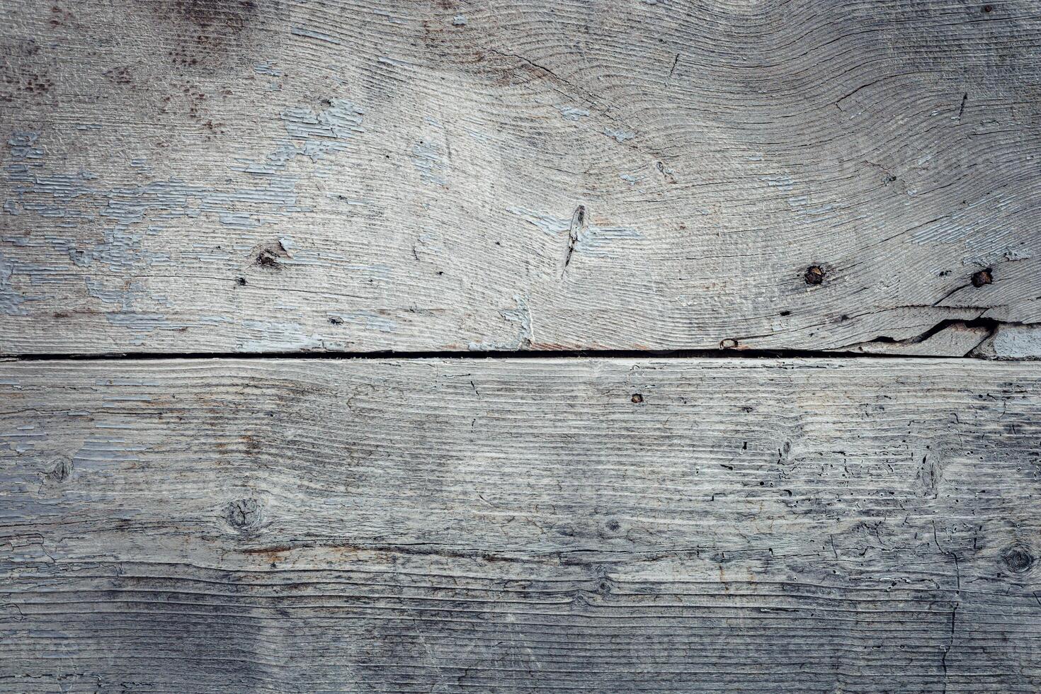 Close-up of weathered wooden planks with a grayish tone. The surface shows natural textures and imperfections, ideal for backgrounds or rustic themes. photo
