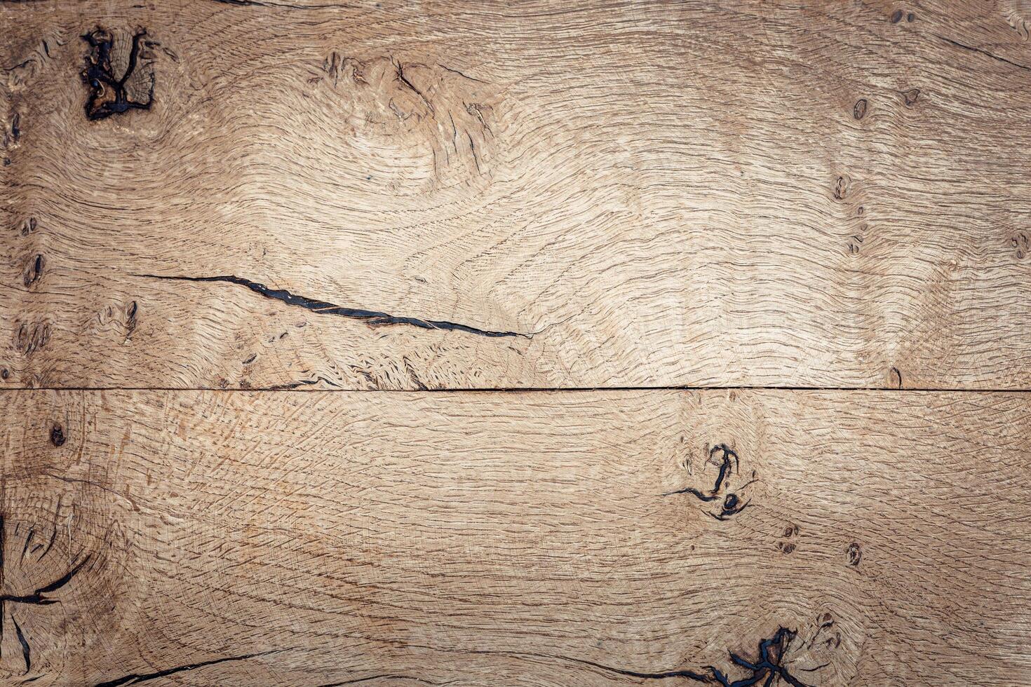 Close-up of a textured wooden surface with natural grain patterns. The wood is light-colored with visible knots and lines, creating a rustic appearance. photo
