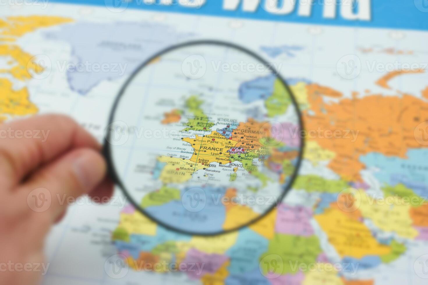 Exploring countries through a magnifying glass on a world map highlighting France and its neighbors photo