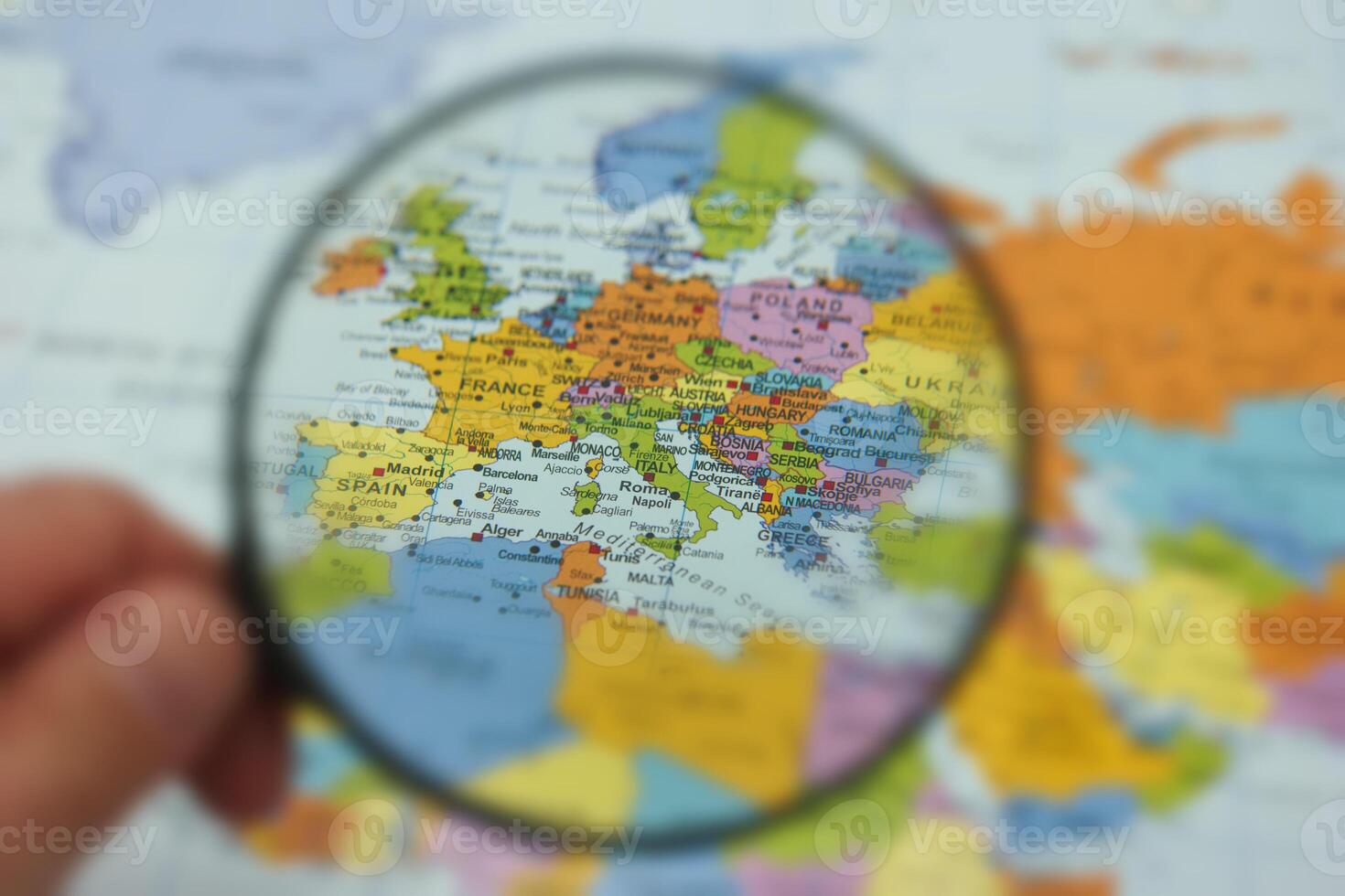 Exploring Europe with a magnifying glass on a detailed map highlighting countries and cities photo