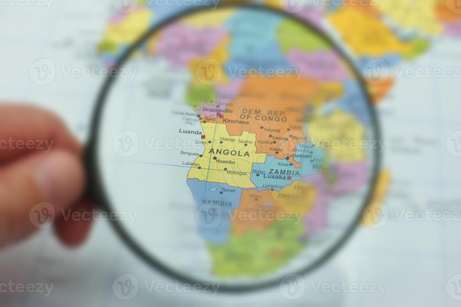 Exploring Angola on a detailed map with a magnifying glass highlighting its geographic features and neighboring countries photo