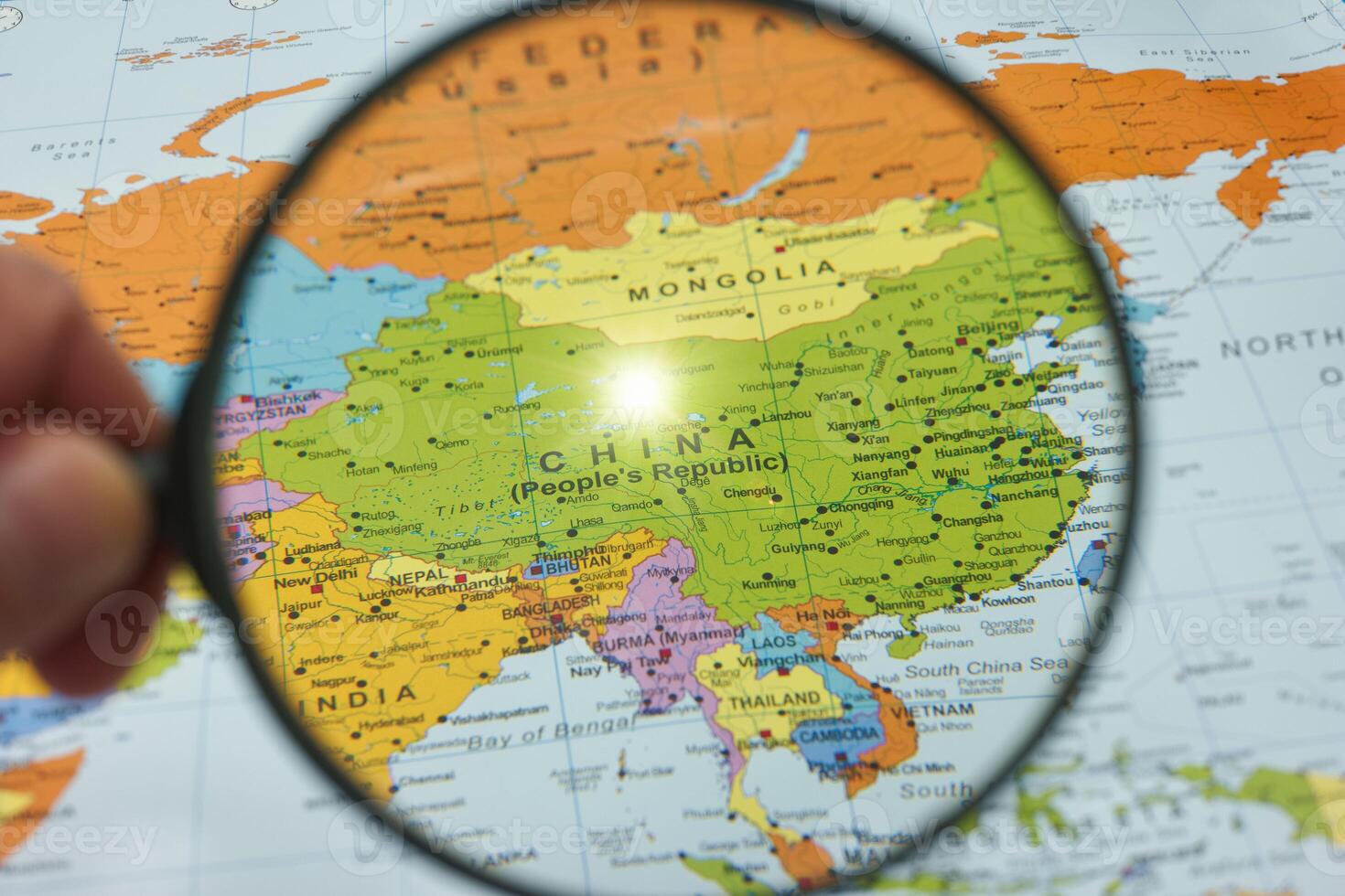 Exploring the geography of China with a magnifying glass on a detailed map reflecting the country's vastness and neighboring regions photo